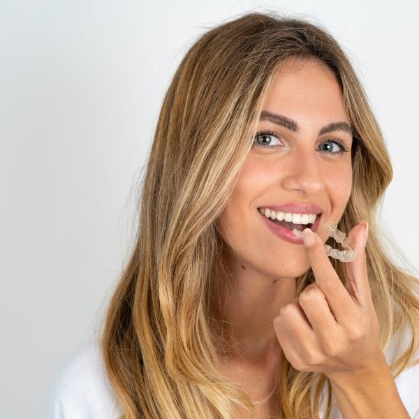 MODEL holding an invisible aligner ready to use it. Dental healthcare and confidence concept.